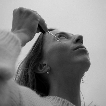 Nahaufnahme des Glow Serums mit glitzerndem Inhalt in einem transparenten Tropfflaschen-Design.