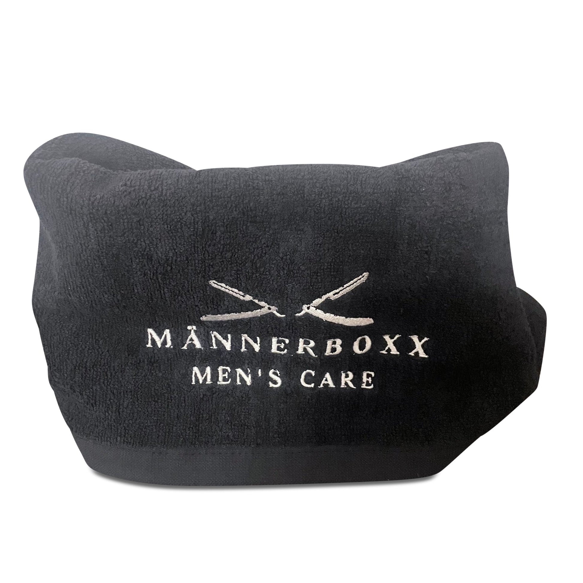 Rasiertuch von Männerboxx in der Nähe von Rasierer und Pflegeprodukten auf einem Badetisch.