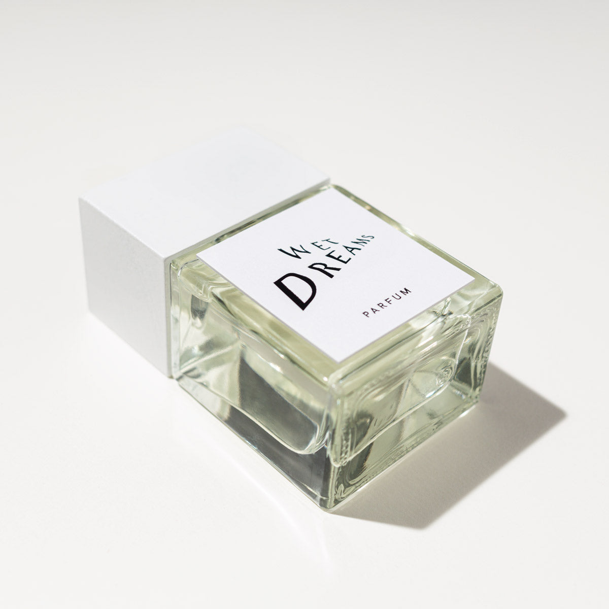 WET DREAMS Parfum auf einem stilvollen Tisch, umgeben von Himbeeren, die den frischen Duft des Unisex Parfums darstellen.