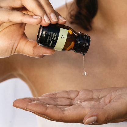 Nahaufnahme des Gesichtsöls balm 002 mit goldenen Reflexen und sanften Tropfen auf einem Holzuntergrund.