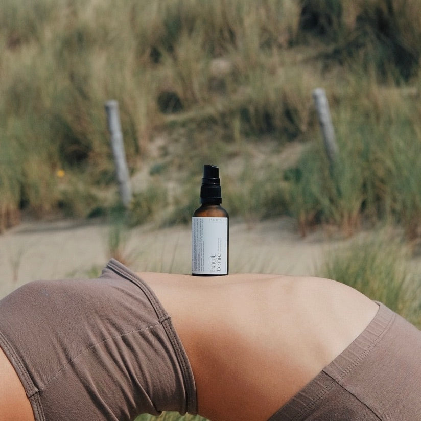 Hauttonic auf einem Holz-Tisch, umgeben von frischen Rosen, symbolisiert natürliche Hautpflege