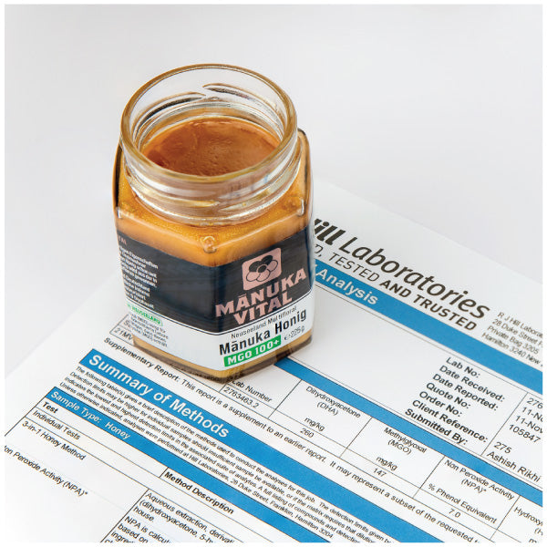 Ein Löffel Manuka Honig MGO 100+ auf einem hellen Teller, zeigt die goldene, dicke Konsistenz.