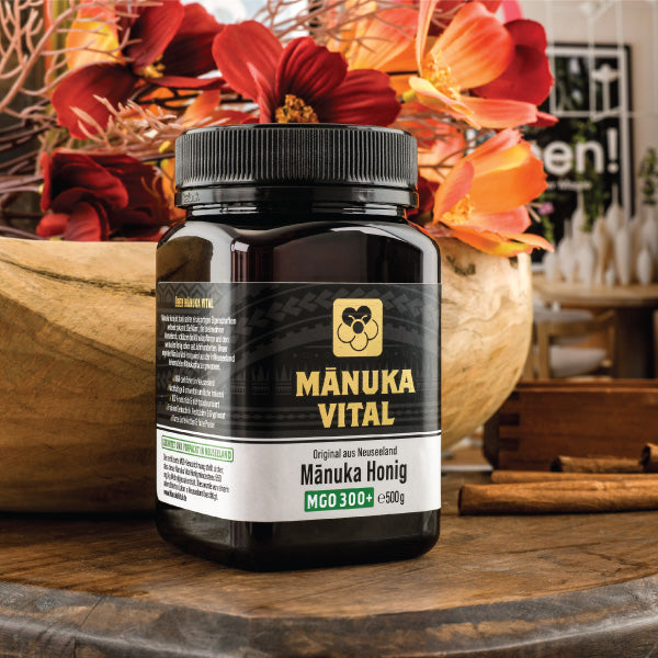 Ekovita Manuka Honig MGO 300+ in 500g Glas mit ansprechender Premium-Verpackung auf einem Holztisch.